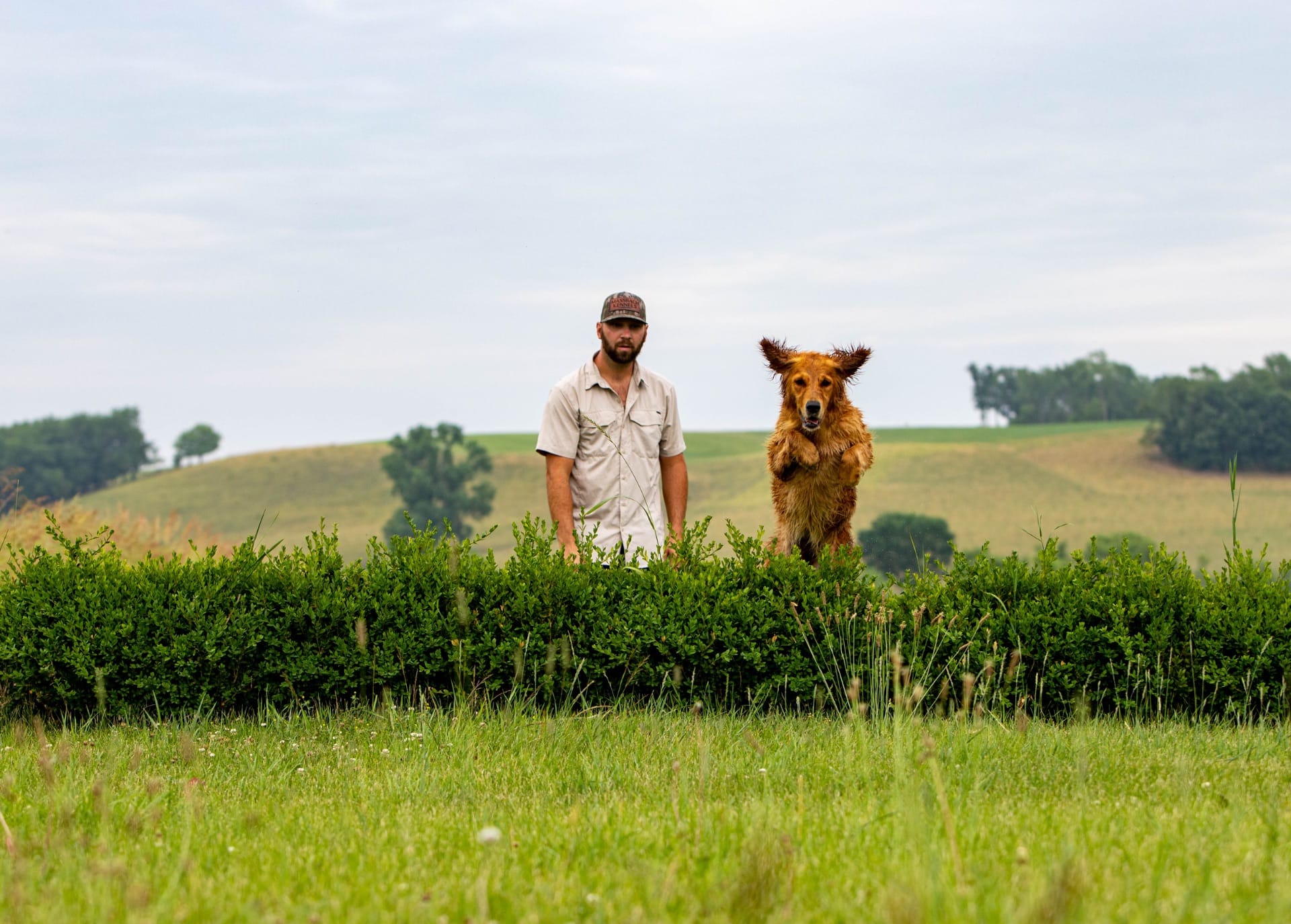 Massbach trainer standing with a golden retriever on a hillside