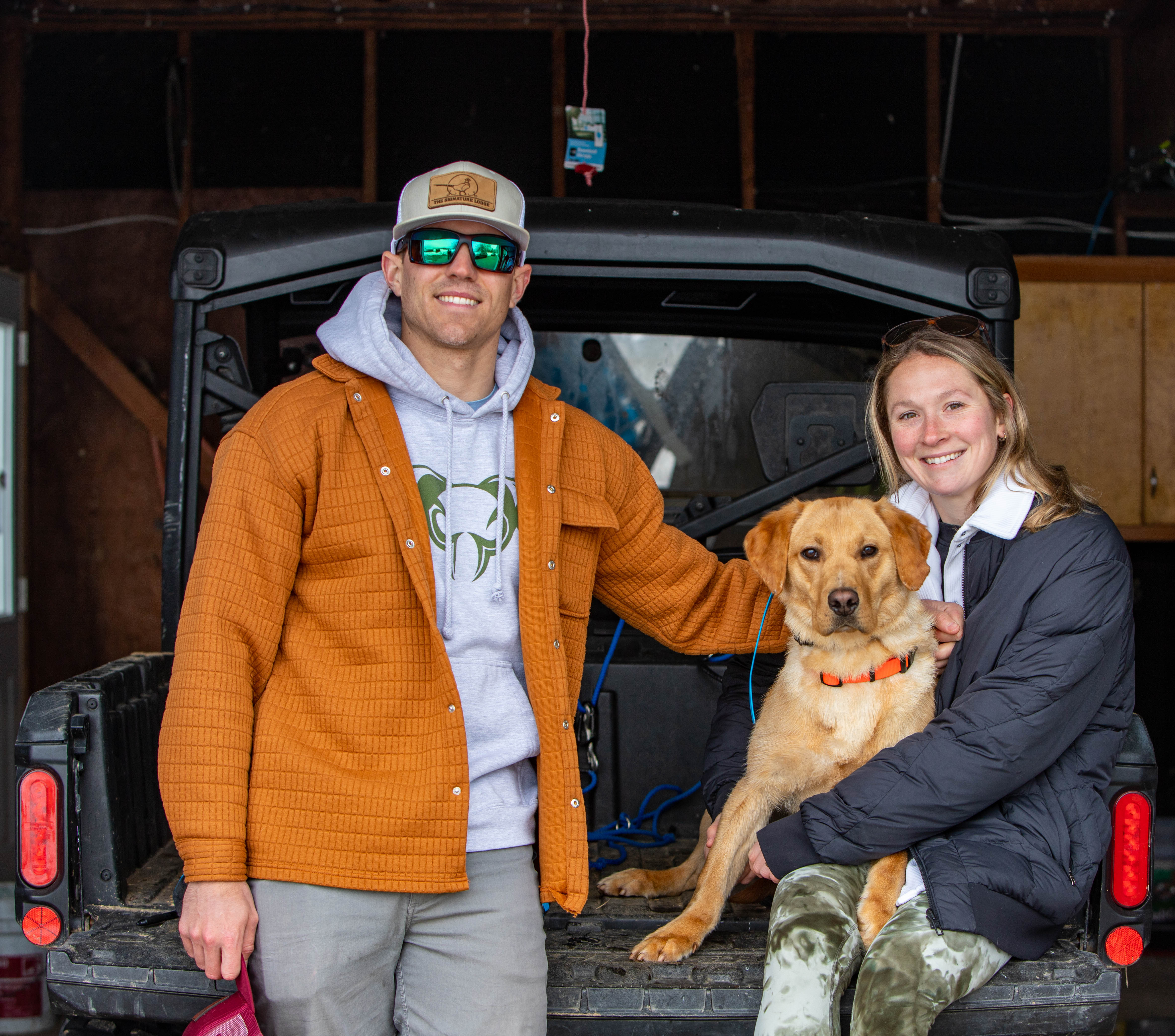 Owners with their yellow Labrador in the back of their truck